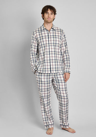 A man wearing a cream pajama set with a red, blue, and yellow madras print stands in front of a plain background. 