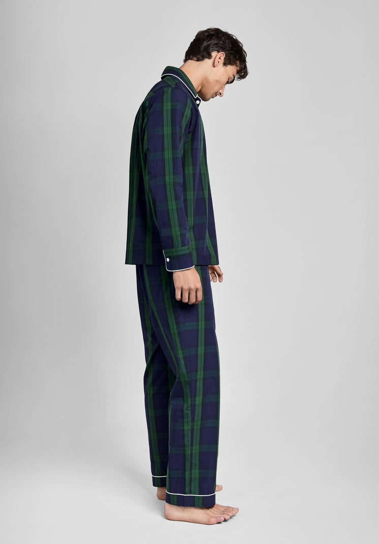 Man wearing a green and navy blackwatch plaid pajama set on a light grey background