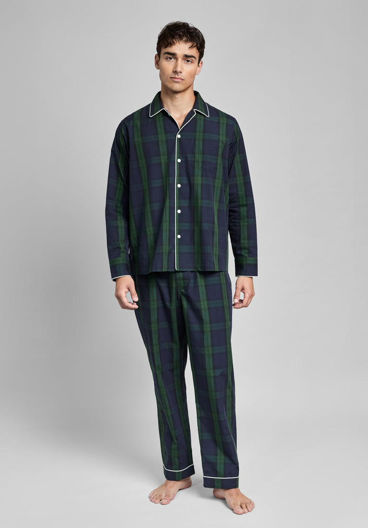 Man wearing a dark green and navy blackwatch plaid pajama set on a gray background
