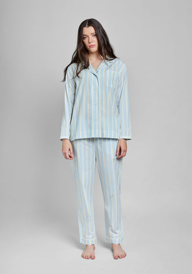 Woman wearing a light blue striped pajama set on a gray background
