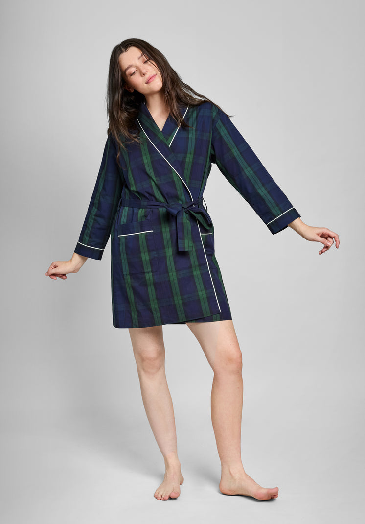 Woman wearing a navy and green blackwatch plaid robe with white piping on a gray background