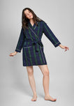 Woman wearing a navy and green blackwatch plaid robe with white piping on a gray background
