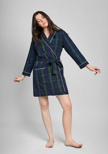 Woman wearing a navy and green blackwatch plaid robe with white piping on a gray background