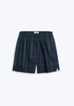 Navy and green blackwatch plaid boxer with sheep logo label on short hem on grey background.