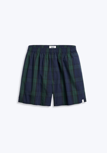 Navy and green blackwatch plaid boxer with sheep logo label on short hem on grey background.