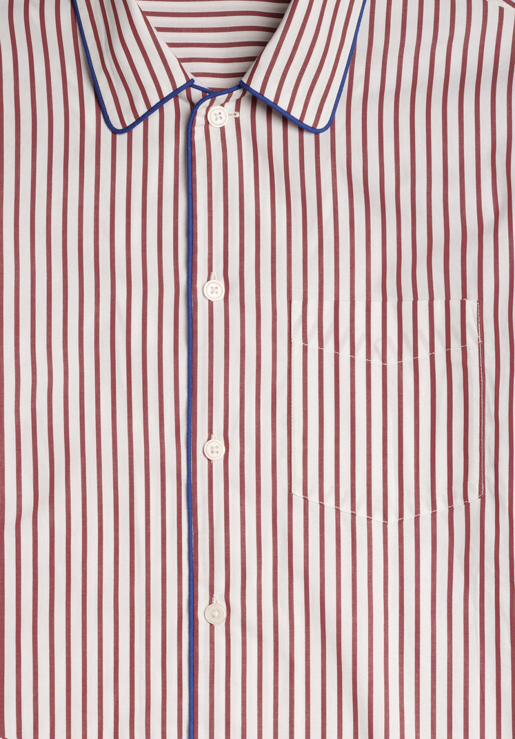 Close-up of a burgundy and white striped pajama shirt with blue trim.