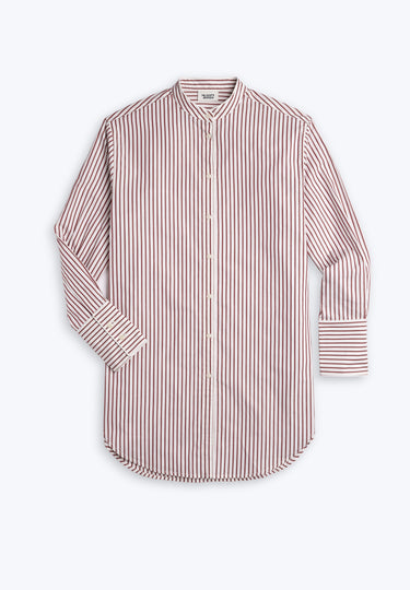 Woman wearing burgundy and white striped nightdress bending down and putting on blue socks. 