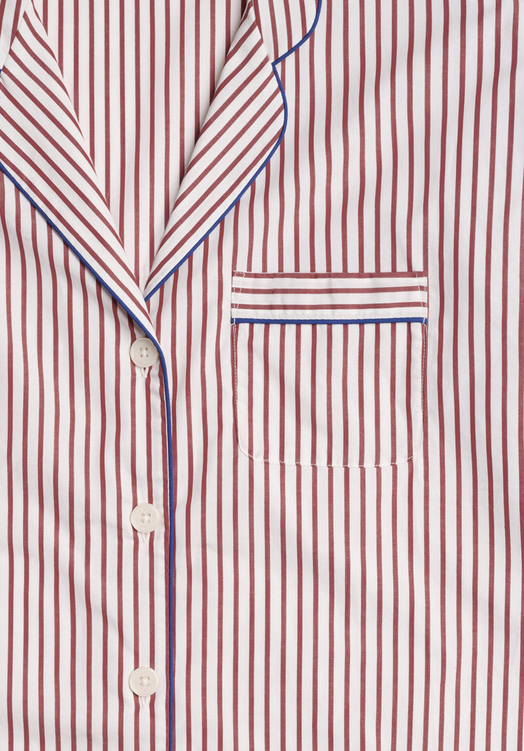 Close-up of the collar and chest pocket of a burgundy and white striped pajama shirt with blue piping.