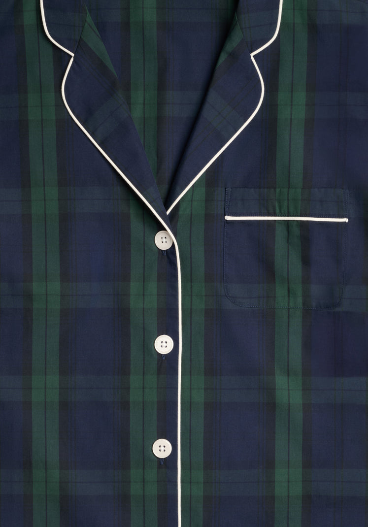 Close up of the collar, chestpocket, and front buttons of a navy blue and green blackwatch plaid pajama top with white buttons and white piping. 