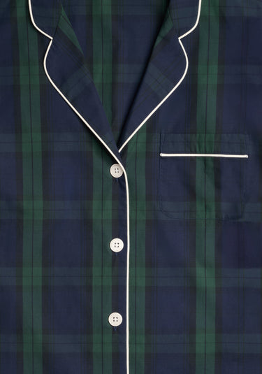 Close up of the collar, chestpocket, and front buttons of a navy blue and green blackwatch plaid pajama top with white buttons and white piping. 