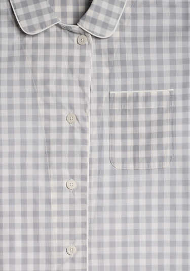 a close up photo of the collar detail, buttons, and chest pocket of a grey and white gingham pajama top