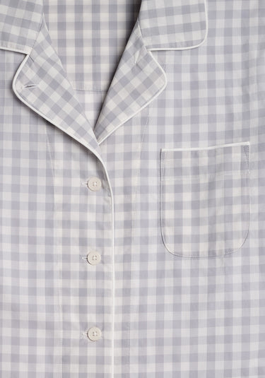 a close up photo of the collar detail, buttons, and chest pocket of a grey and white gingham pajama top.