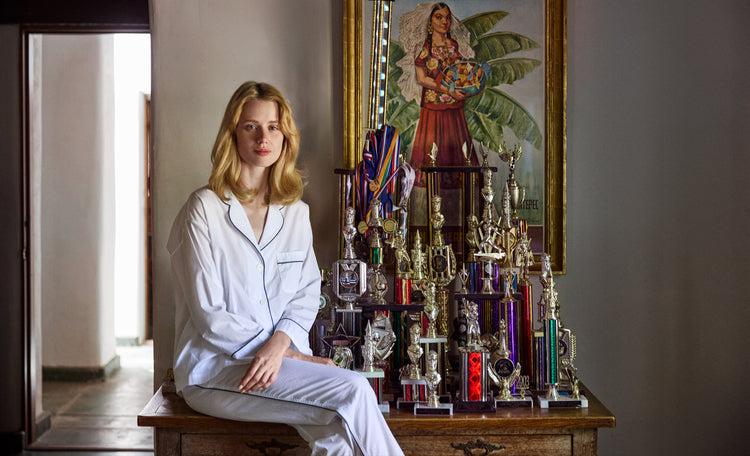 a woman sitting next to trophies wearing a white pajama set.
