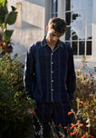 Man wearing green and navy blackwatch plaid pajamas in a garden.