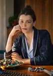 Woman in a blackwatch robe sitting at a table with a bowl full of wrapped chocolates.