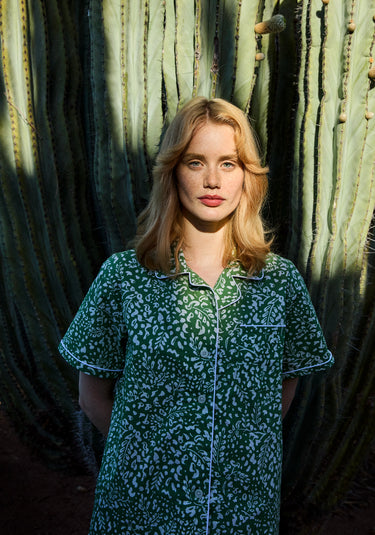 Woman in a green leaf printed pajama shirt standing in front of cacti