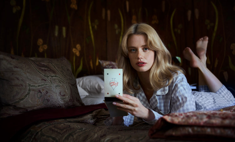 Woman lying on a bed holding a notebook with a floral design.